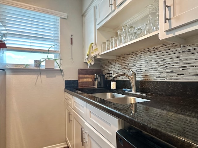 bar featuring sink, dark stone countertops, backsplash, and white cabinetry