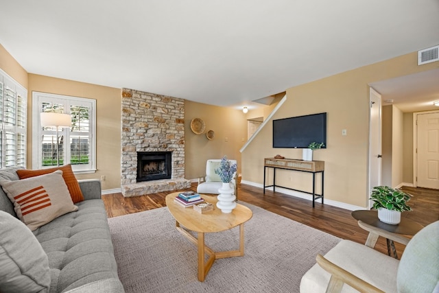 living room with wood-type flooring and a stone fireplace