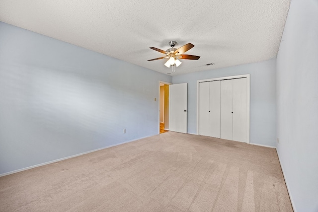 unfurnished bedroom featuring a textured ceiling, ceiling fan, light carpet, and a closet