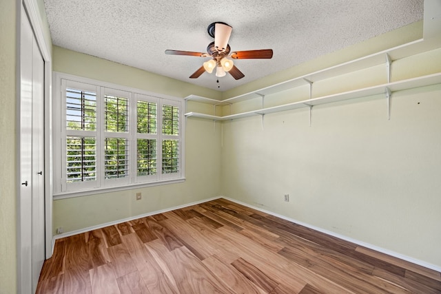 empty room with ceiling fan, a textured ceiling, and light hardwood / wood-style flooring