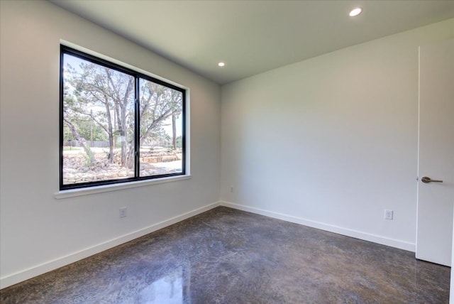 spare room with concrete floors, baseboards, and recessed lighting