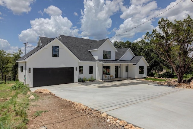 modern inspired farmhouse with concrete driveway, metal roof, an attached garage, a standing seam roof, and stucco siding