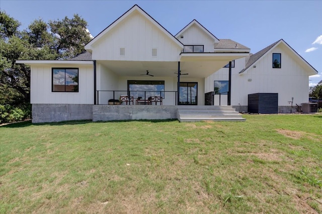 rear view of house featuring ceiling fan, a lawn, and board and batten siding