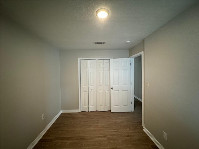 101 S Lockhart St, Manor, TX 78653 - unfurnished bedroom featuring a textured ceiling, visible vents, baseboards, a closet, and dark wood-style floors