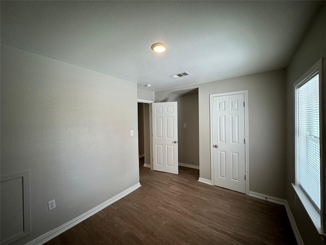 101 S Lockhart St, Manor, TX 78653 - unfurnished bedroom with baseboards, dark wood-style floors, multiple windows, and visible vents