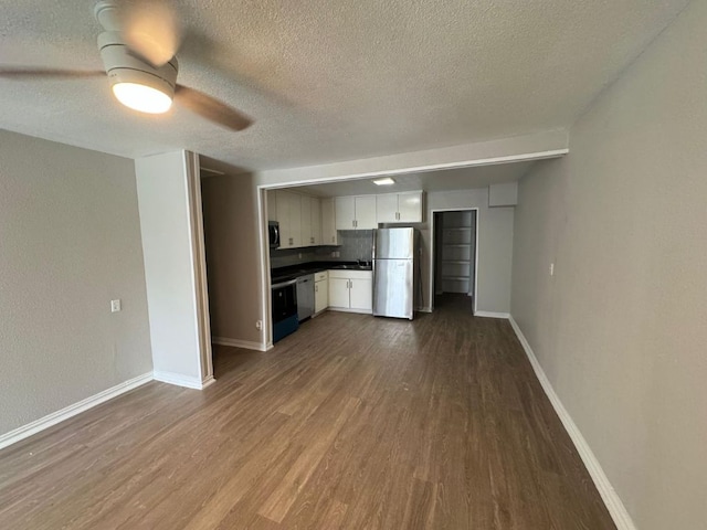 101 S Lockhart St, Manor, TX 78653 - unfurnished living room featuring a textured ceiling, ceiling fan, baseboards, and dark wood-type flooring