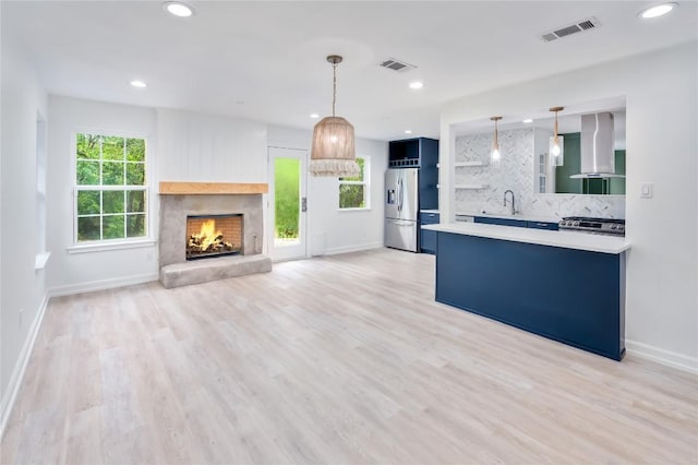 kitchen with sink, stainless steel appliances, tasteful backsplash, extractor fan, and decorative light fixtures