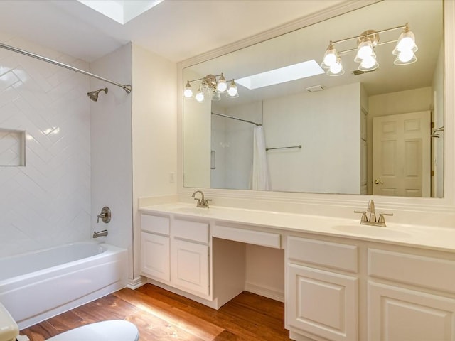 bathroom with hardwood / wood-style flooring, shower / bathtub combination with curtain, vanity, and a skylight