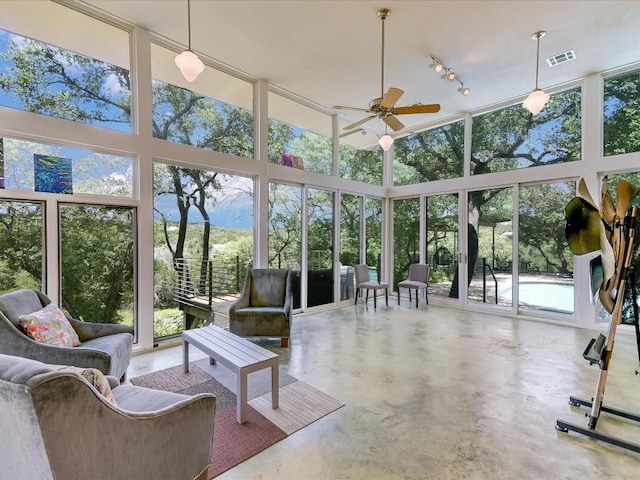 sunroom / solarium with ceiling fan, track lighting, and a healthy amount of sunlight