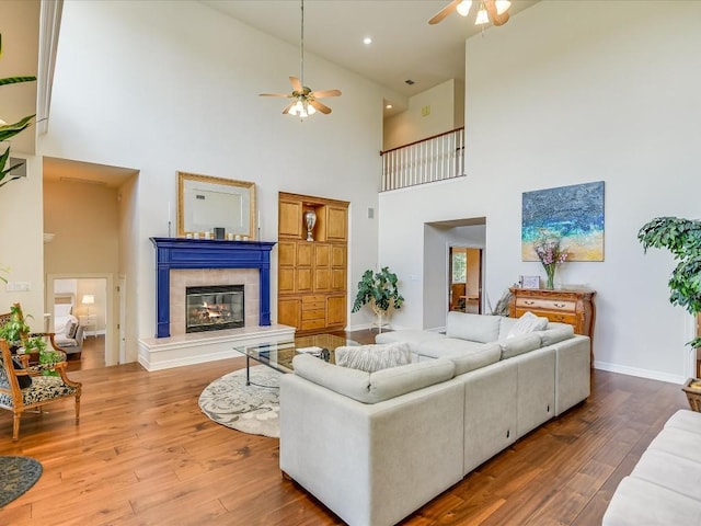 living room featuring ceiling fan, a tiled fireplace, and hardwood / wood-style floors