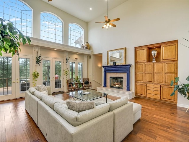 living room with a tile fireplace, french doors, plenty of natural light, and hardwood / wood-style flooring