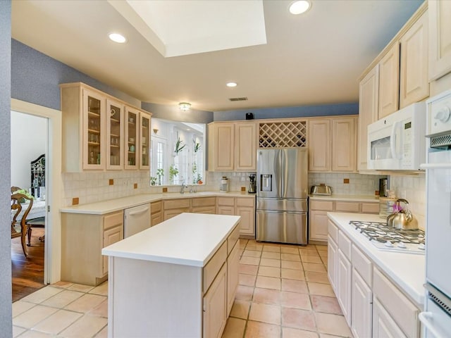 kitchen with white appliances, light tile patterned floors, a kitchen island, and backsplash