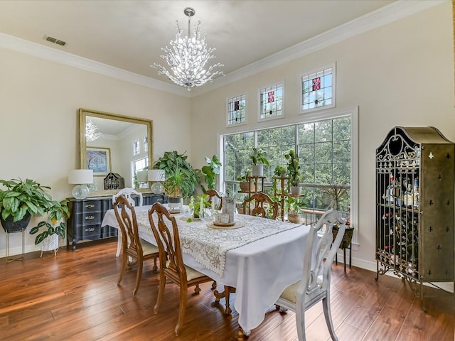 dining room with dark hardwood / wood-style flooring, crown molding, and an inviting chandelier