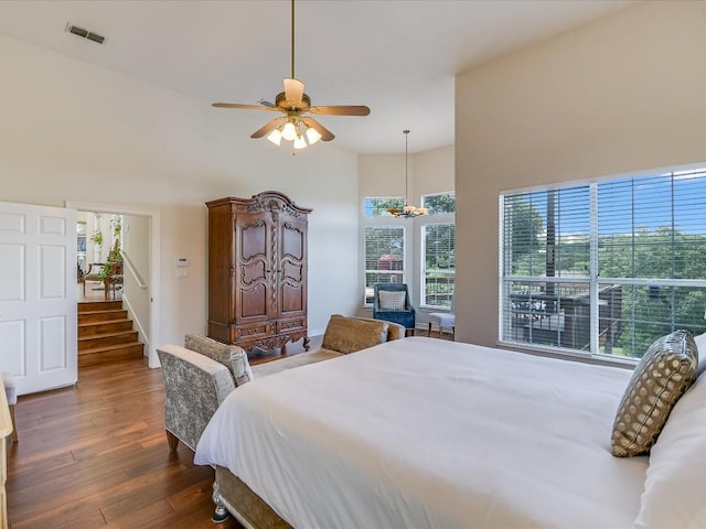 bedroom featuring ceiling fan, dark hardwood / wood-style floors, and a towering ceiling