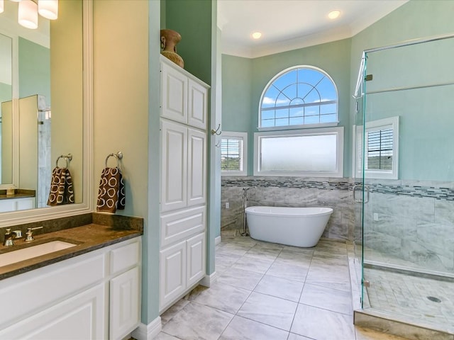 bathroom with tile patterned flooring, tile walls, independent shower and bath, vanity, and crown molding