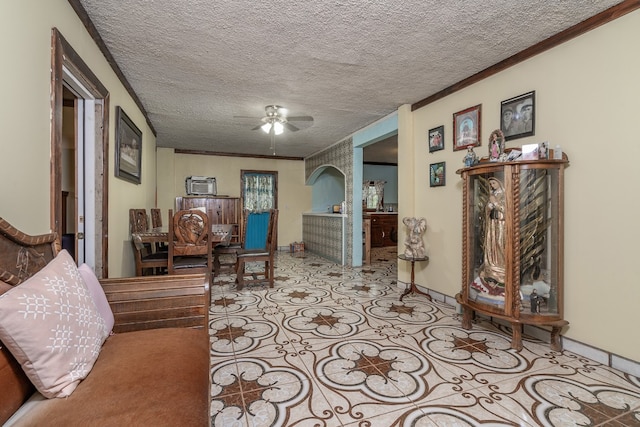 tiled living room with ceiling fan, a textured ceiling, and crown molding