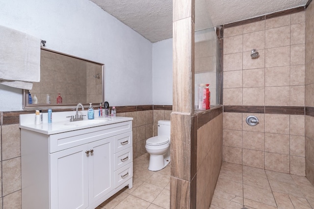 bathroom with a tile shower, tile flooring, vanity with extensive cabinet space, and tile walls