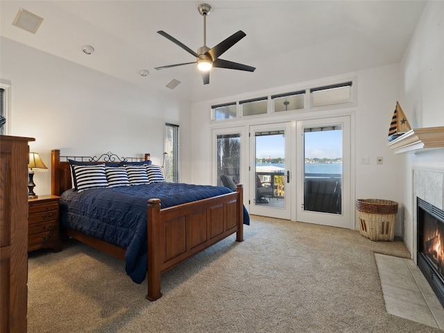 carpeted bedroom featuring ceiling fan, a tile fireplace, and access to exterior