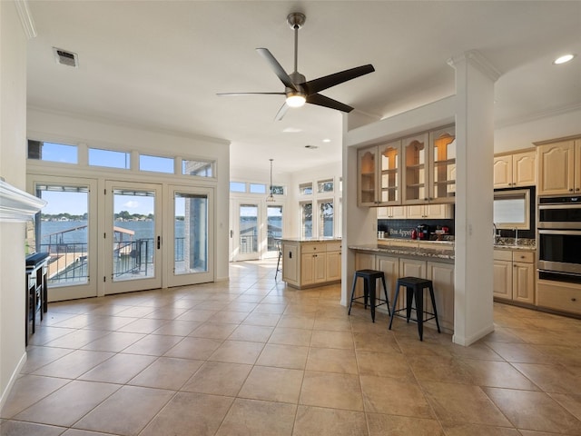 kitchen featuring a kitchen breakfast bar, stainless steel double oven, ornamental molding, and ceiling fan