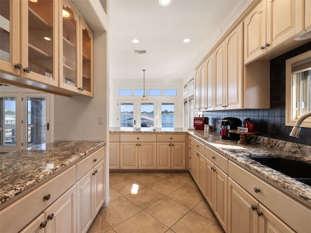 kitchen featuring pendant lighting, backsplash, light tile floors, ornamental molding, and stone countertops