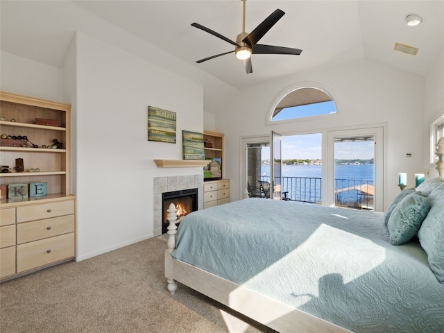 bedroom featuring ceiling fan, a water view, a tile fireplace, carpet, and access to exterior