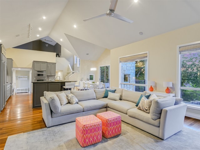 living room with ceiling fan, vaulted ceiling, and light hardwood / wood-style flooring