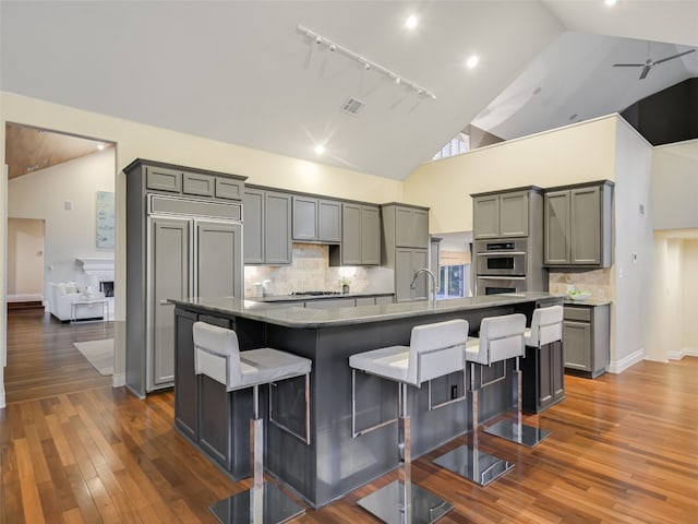 kitchen with a kitchen bar, tasteful backsplash, gray cabinets, and a spacious island