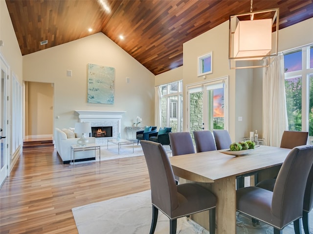 dining room with light wood-type flooring, high vaulted ceiling, and wooden ceiling