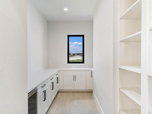 bar featuring white cabinetry, light hardwood / wood-style flooring, and wine cooler