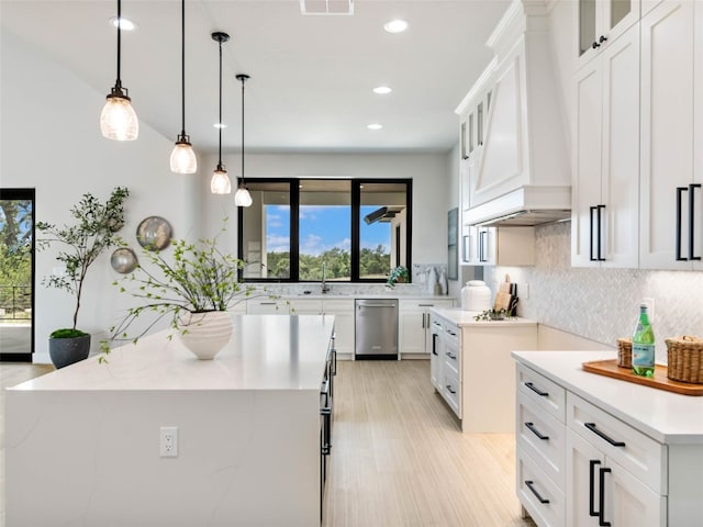 kitchen featuring a kitchen island, dishwasher, white cabinets, decorative backsplash, and hanging light fixtures