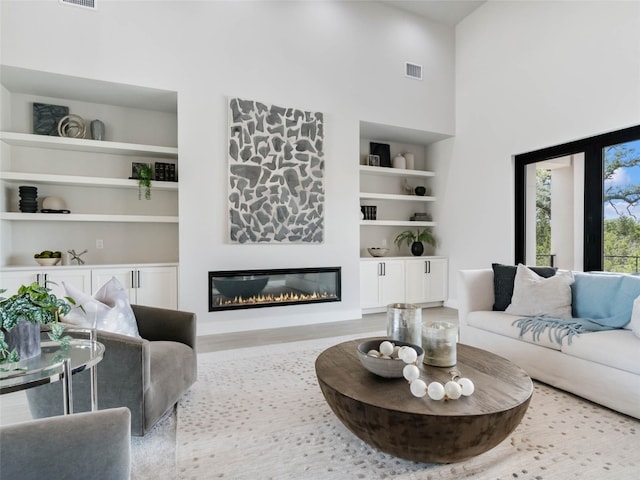 living room with a towering ceiling and built in shelves