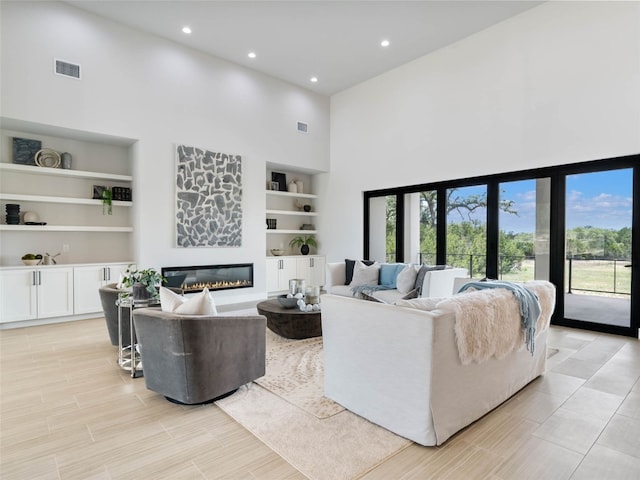 living room with built in shelves and a towering ceiling