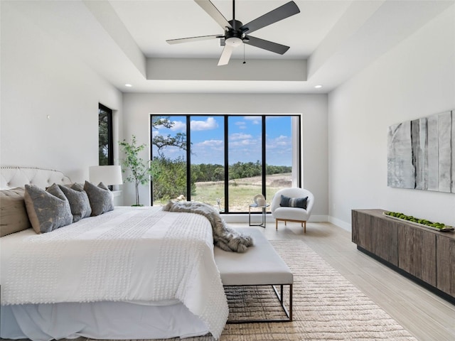 bedroom featuring a tray ceiling, light hardwood / wood-style floors, and ceiling fan