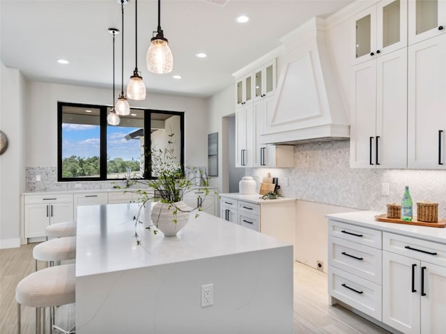 kitchen with premium range hood, a kitchen island, and white cabinets