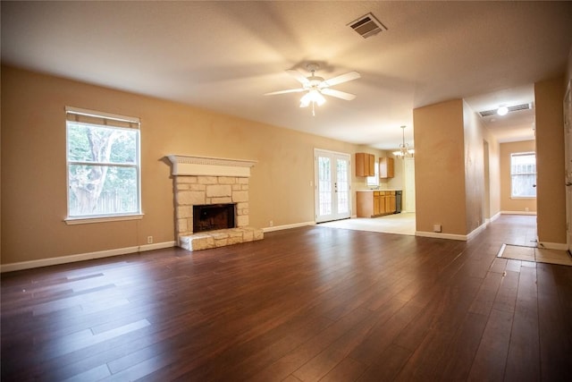 unfurnished living room featuring a fireplace, ceiling fan with notable chandelier, and dark hardwood / wood-style floors