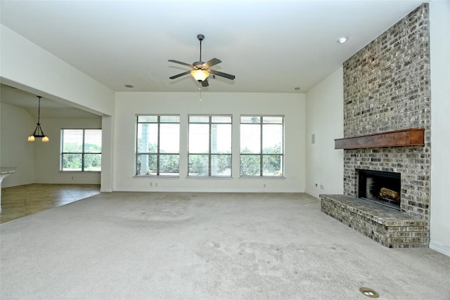 unfurnished living room featuring ceiling fan, a fireplace, and light colored carpet