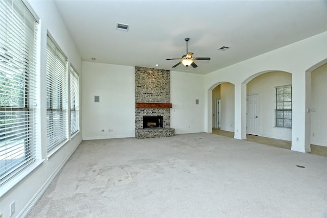 unfurnished living room featuring a fireplace, light colored carpet, and ceiling fan