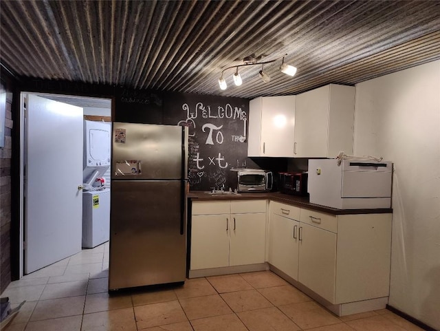 kitchen with white cabinetry, stainless steel fridge, light tile patterned floors, and washer / dryer