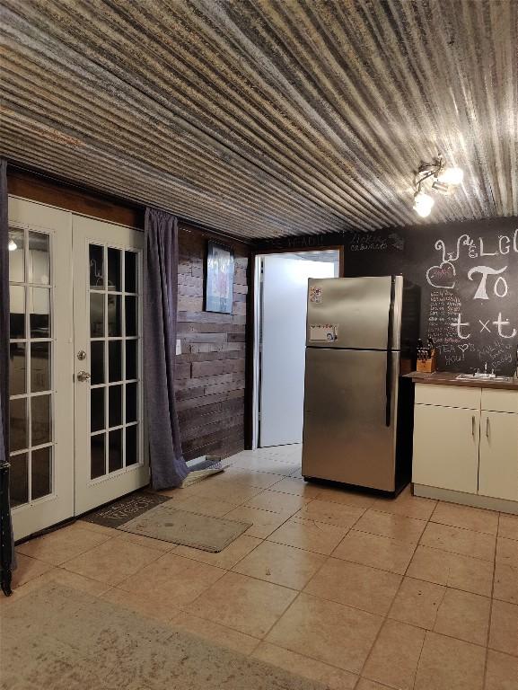 kitchen featuring french doors, white cabinetry, stainless steel refrigerator, and sink