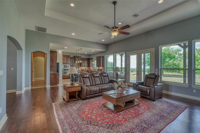 living room featuring ceiling fan, dark hardwood / wood-style flooring, and a tray ceiling