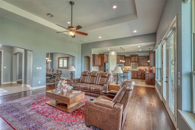 living room featuring ceiling fan, hardwood / wood-style flooring, and a tray ceiling