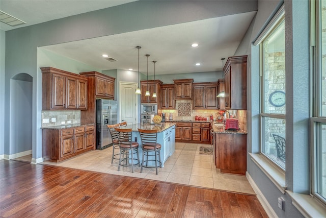 kitchen with backsplash, appliances with stainless steel finishes, dark stone countertops, and a center island