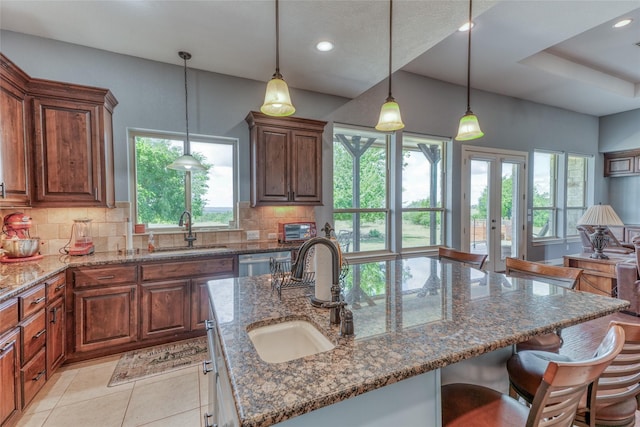 kitchen featuring backsplash, a center island with sink, and sink