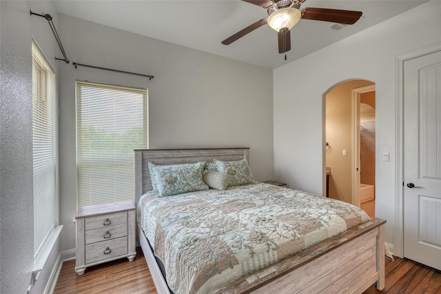 bedroom featuring ceiling fan, ensuite bath, and hardwood / wood-style flooring