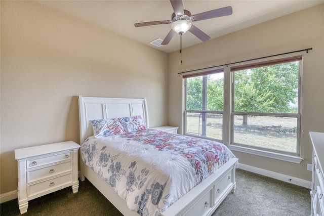 bedroom with ceiling fan, dark colored carpet, and multiple windows