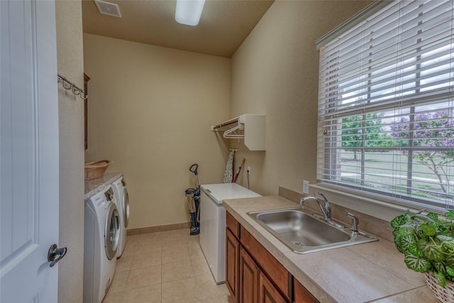 clothes washing area with light tile patterned floors, separate washer and dryer, a textured ceiling, cabinets, and sink