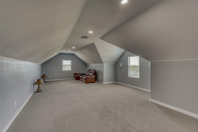 additional living space featuring light carpet, lofted ceiling, and plenty of natural light