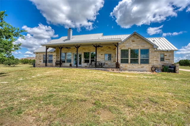 rear view of house with ceiling fan, a patio area, and a yard