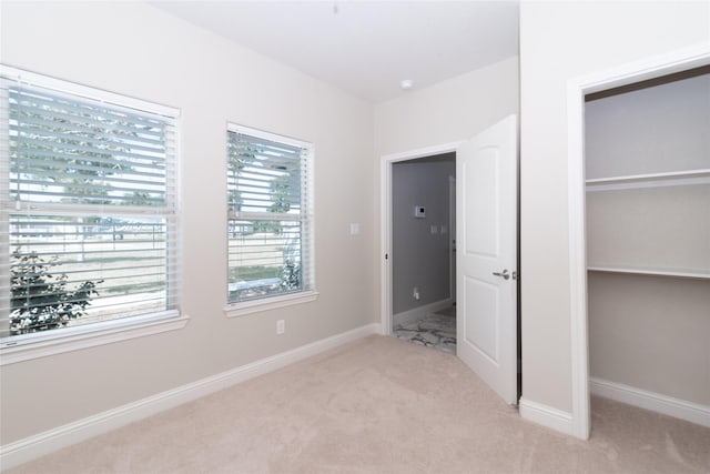 unfurnished bedroom featuring light carpet and a closet