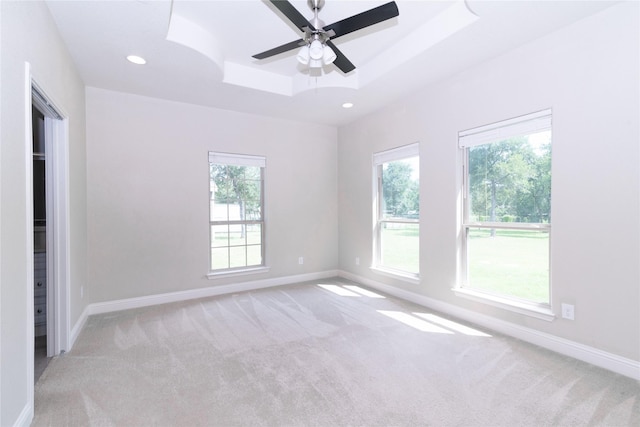 carpeted spare room with ceiling fan and a tray ceiling